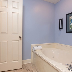 Indulge in relaxation with a jetted tub, soft towels, and soothing blue walls in this inviting master bath