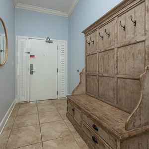 Welcoming entryway featuring a rustic bench, light blue walls, and a round mirror for a cozy ambiance