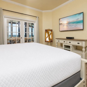 Cozy master bedroom featuring a king bed, a large TV, and elegant French doors leading to a scenic living space