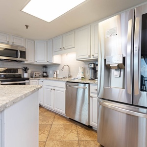 Bright kitchen featuring white cabinetry, granite countertops, stainless appliances, and a coffee station 
