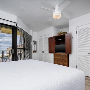 This bedroom features a cozy bed, a TV for entertainment, and a lovely gulf view from the balcony