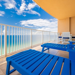 Relax on vibrant blue loungers, soaking in expansive views and the refreshing breeze from your balcony