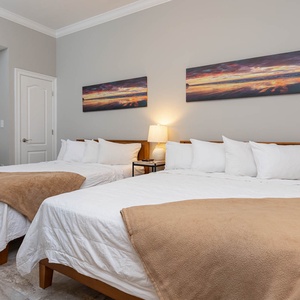 Doze on two roomy queen beds beneath coastal sunset canvases in this stylish guest room