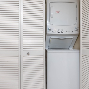 Convenient stacked washer and dryer tucked behind stylish white louvered doors for easy laundry access during your stay