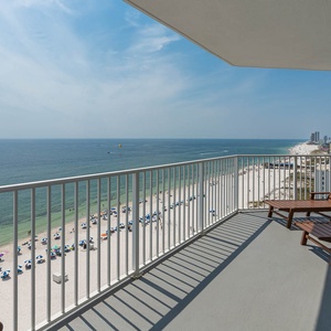 This balcony features two wooden lounge chairs with a stunning beachfront view, perfect for relaxing and enjoying the scenery