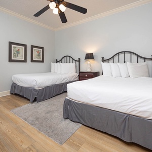 Rest in this inviting guest bedroom featuring two double beds, warm decor, and soft lighting for a relaxing stay