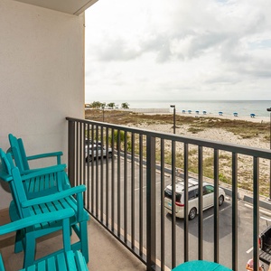 This balcony features bright turquoise chairs and offers a beautiful view of the beach, perfect for relaxation