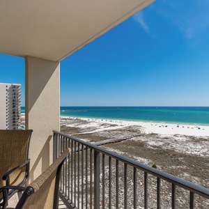 Serene balcony view of the beach with its white sand and turquoise waters, perfect for relaxation