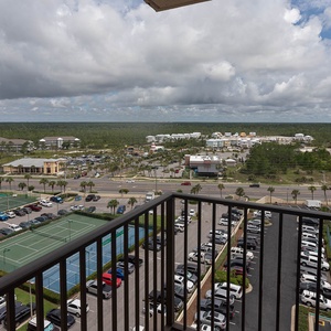 The view from the master balcony showcases a vibrant landscape with tennis courts