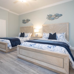 Unwind on the plush queen beds beneath fish wall art and read by the warm bedside lamp in this guest suite