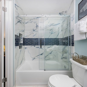 Marble-patterned walls and blue tile frame the tub in this guest bath for your refreshing escape