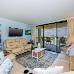 This condo features plush leather seating, a large TV, and a serene river view from the balcony