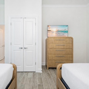 Cozy guest bedroom featuring two beds, a stylish dresser, and a TV