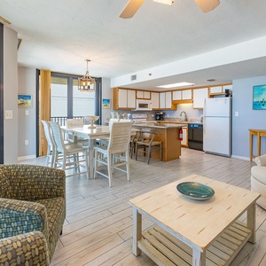 Dining area featuring a whitewashed table and chairs, with sliding doors opening to a beach balcony