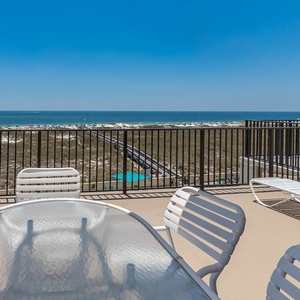 Extended balcony seating offers a relaxing spot to enjoy the expansive beach view and gentle gulf waves in the distance