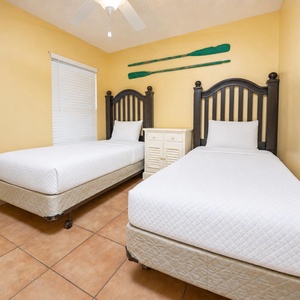 Relaxing guest bedroom featuring two twin beds and cheerful yellow walls, perfect for a cozy stay