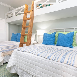 Charming bunk room with two lofted twin beds above two cozy queen beds below