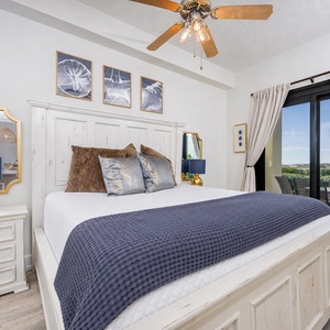 Cozy master suite featuring a king bed, a stylish lamp, and direct access to a patio with a beach view