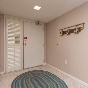 Welcoming entryway features a round rug, coat hooks, and a door with a window, creating a cozy atmosphere for guests