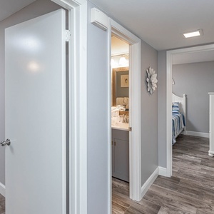 Step into a welcoming hallway that leads to a bright bathroom and a cozy bedroom with charming decor and soft bedding