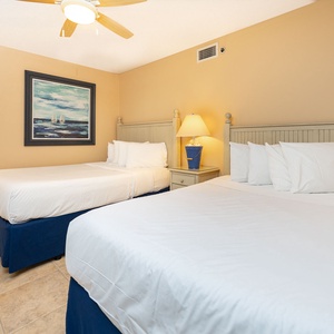 A queen and a double bed complemented by a bedside lamp create a relaxed atmosphere in this inviting guest room