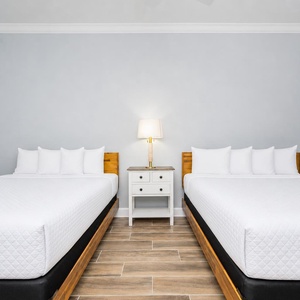 Rest comfortably in this guest room featuring two queen beds, a stylish nightstand, and cheerful coastal artwork
