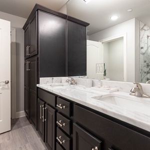 Freshen up at the dual vanity, then step into the glass shower with its rainfall showerhead in the master bath