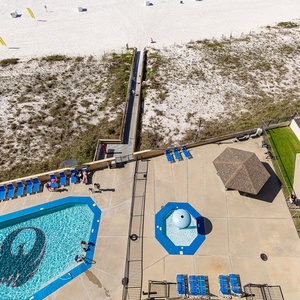 The view showcases a vibrant pool area with lounge chairs and a spacious beachfront, inviting relaxation and fun