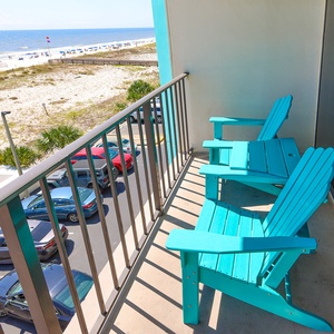 Enjoy the beachfront view from this inviting balcony with bright blue chairs, perfect for relaxation and sunset watching