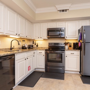 This kitchen features sleek gunmetal appliances, granite countertops, and ample cabinetry for a delightful cooking experience