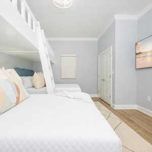 Cozy guest bedroom featuring lofted twin beds, two queen beds below, and a bright atmosphere