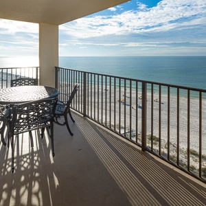 A round table with metal chairs overlooks the tranquil beachfront, inviting guests to enjoy the serene coastal view