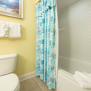 Guest bathroom featuring a playful shower curtain, fresh towels, and a tub/shower for your comfort