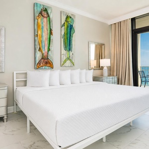 Experience restful nights in the master suite with a king bed, decorative fish art, and beachfront balcony access