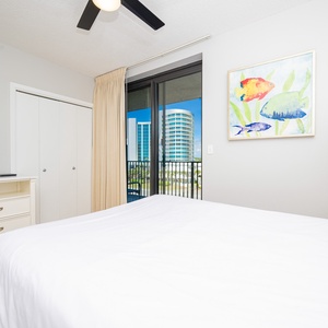 Unwind in this comfortable guest bedroom featuring a cozy queen bed, a TV, and a bright view through the balcony door