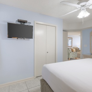 Brightly colored walls complement the king bed, while a wall-mounted TV and mirror enhance this inviting bedroom