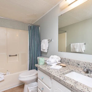 This bathroom features a clean design with a spacious vanity, fresh towels, and a relaxing tub for a rejuvenating experience