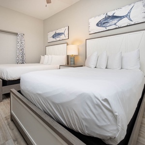 Two double beds with white linens and coastal decor create a serene atmosphere in this inviting guest bedroom