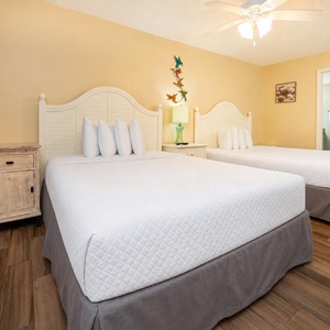 Cheerful guest bedroom featuring two comfortable queen beds, a charming nightstand, and vibrant coastal decor
