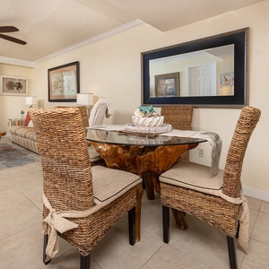 This inviting dining area features a unique wood table, woven chairs, and a view of the beach through large sliding doors