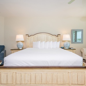 Bright and inviting master bedroom featuring a plush king bed, cozy seating area, and stylish lamps for a relaxing getaway