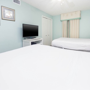 Relax in this cheerful guest room featuring two double beds, a mounted TV, and coastal decor for a refreshing stay