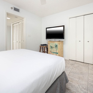 Guest bedroom featuring a comfortable queen bed, a TV mounted on a decorative cabinet, and ample storage space