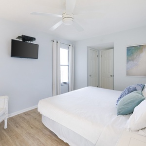 This guest bedroom features a cozy bed, a mounted TV, and soft blue accents, creating a relaxing atmosphere for your stay