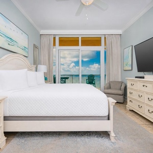 Relax in this serene master bedroom featuring a king bed, large TV, and beachfront balcony access