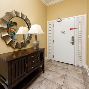 Inviting entryway featuring a stylish mirror, decorative lamp, and colorful artwork for a warm welcome
