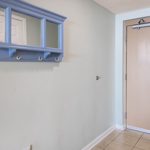 Step into a welcoming entryway featuring a blue coat rack and a mirror, perfect for a quick glance before heading out