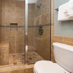Experience a refreshing walk-in shower in the stylish glass-enclosed space with elegant tile and a built-in bench