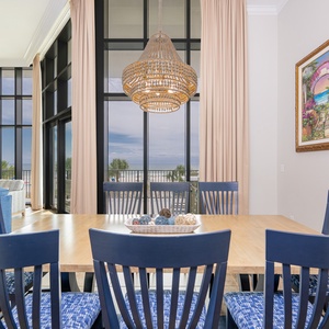 Bright dining area, with seating for eight, featuring a stylish chandelier and inviting views through expansive windows