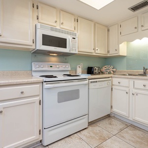 This kitchen features white cabinetry, stainless appliances, and a cheerful coastal color scheme, perfect for meal prep